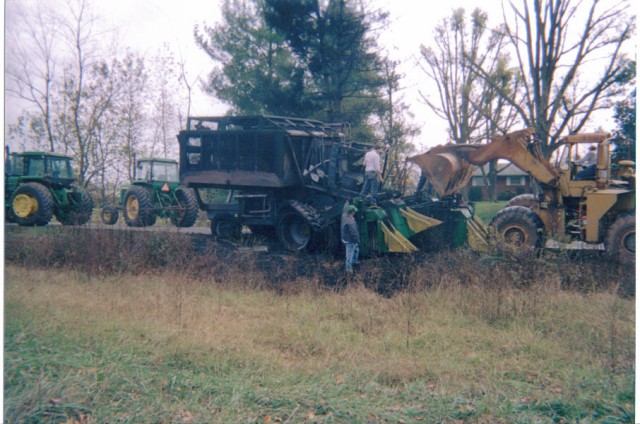 Loading remains of cotton picker on lowboy